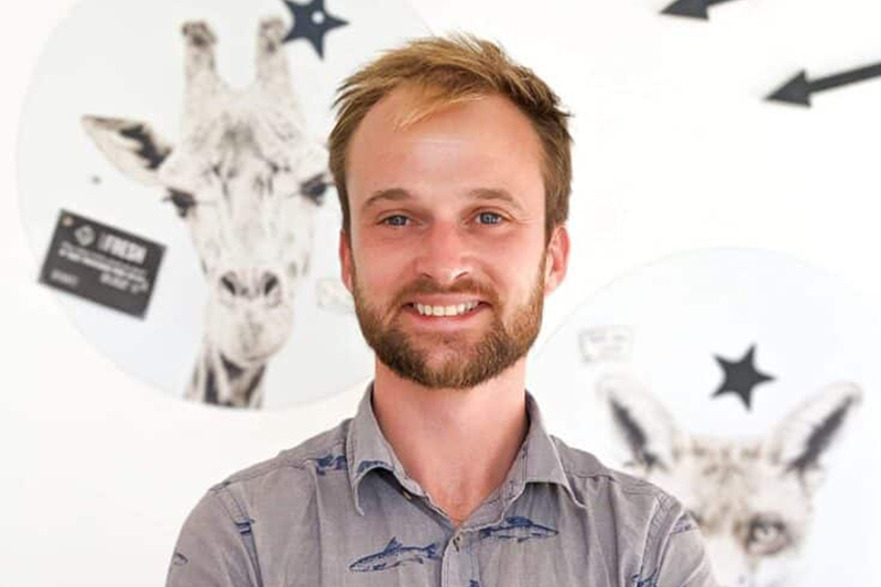 james standing in front of white wall with pictures of animals
