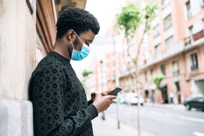 man looking at phone wearing mask