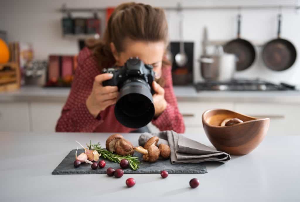 female food blogger photographing fresh produce on a gray napkin in her kitchen