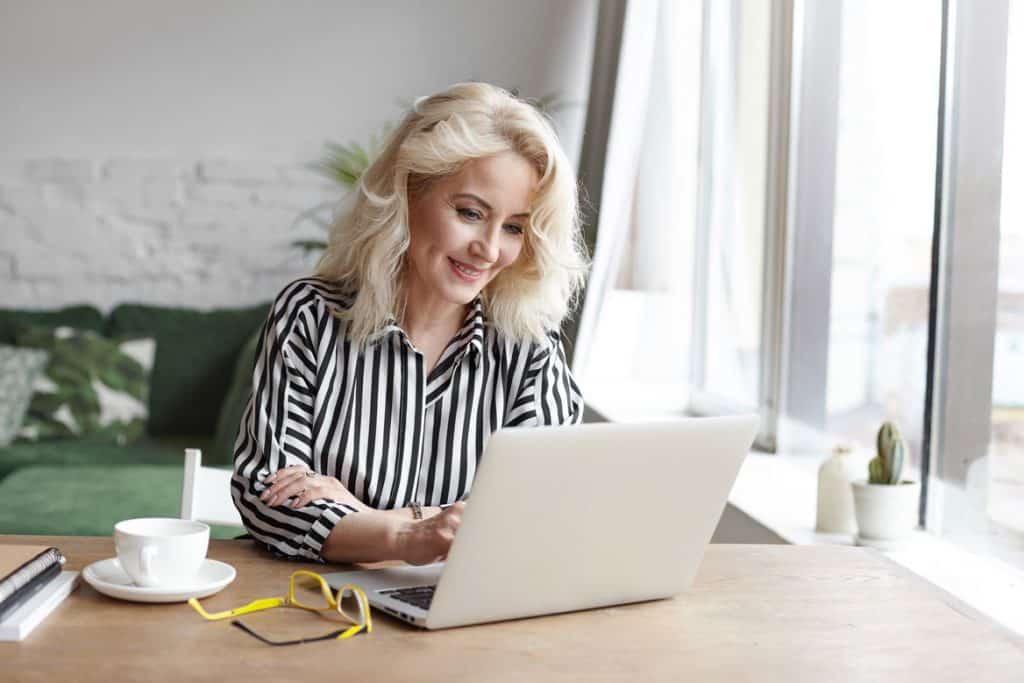 woman at office desk on laptop next to glasses and coffee