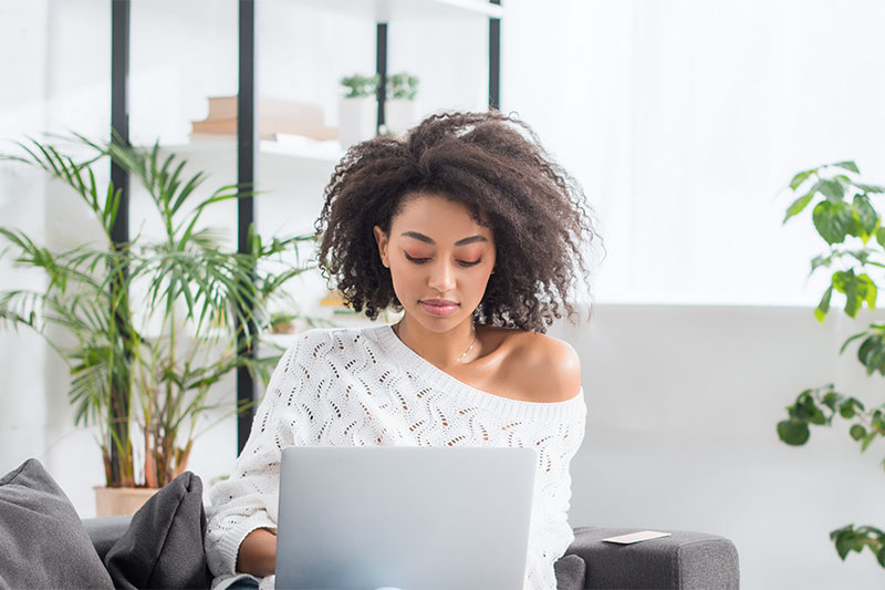 woman looking at her laptop sitting on the couch