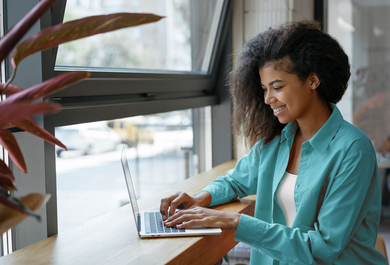 woman using a laptop by a window